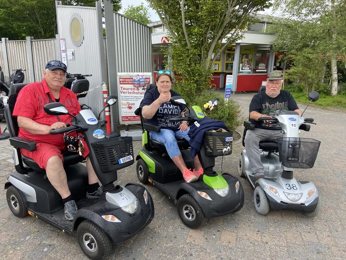 Drei Gäste mit E-Mobilen an der Verleihstation